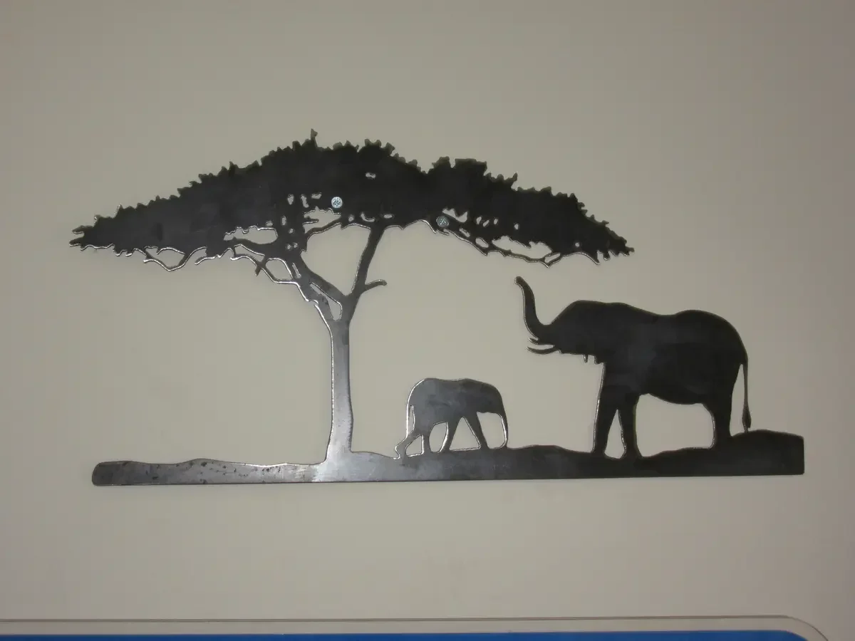 Cut-steel wall panel showing an adult elephant, calf and acacia tree