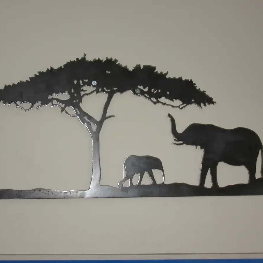 Cut-steel wall panel showing an adult elephant, calf and acacia tree